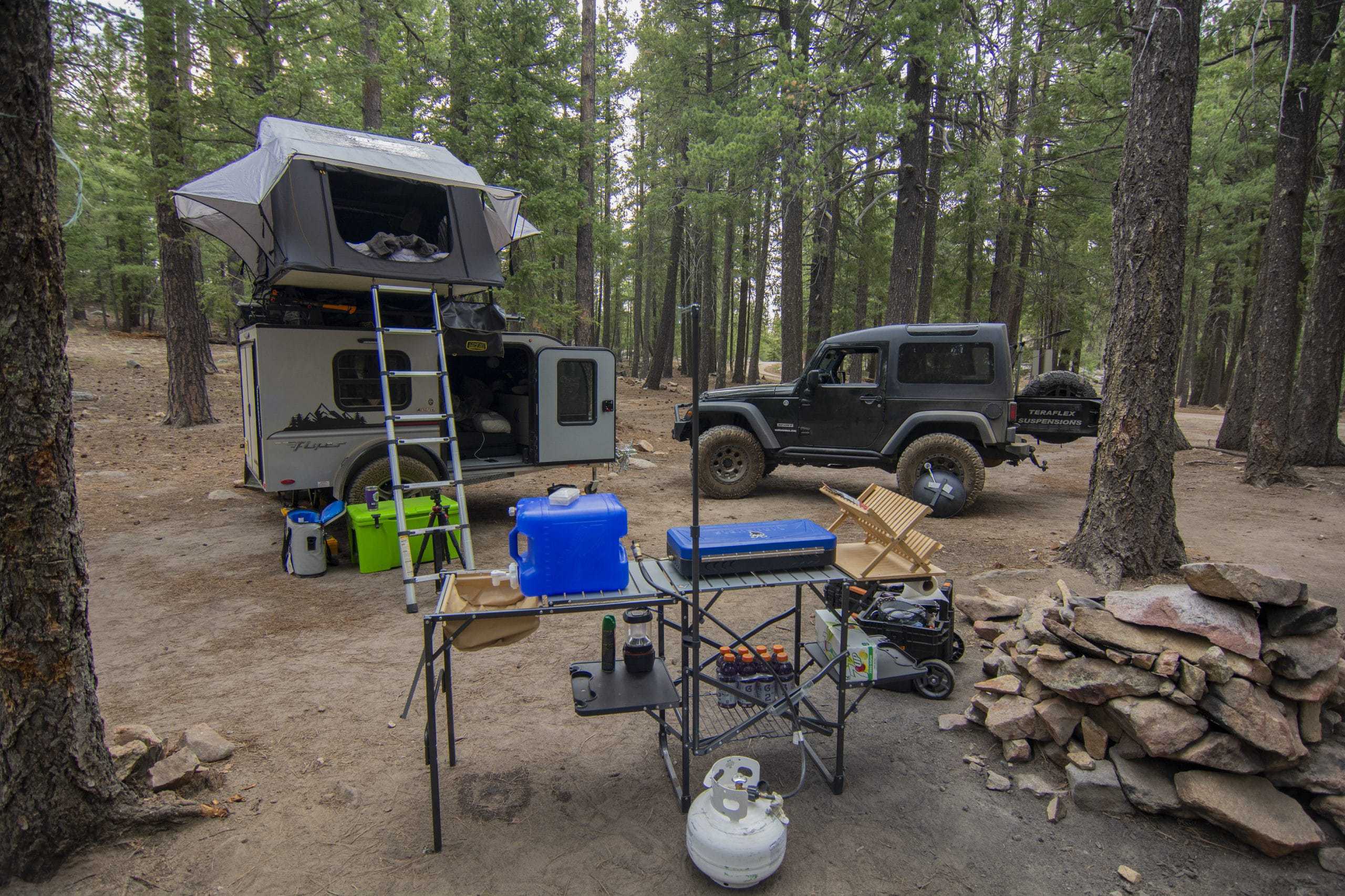 jeep wrangler and squaredrop trailer at a campsite with pine trees