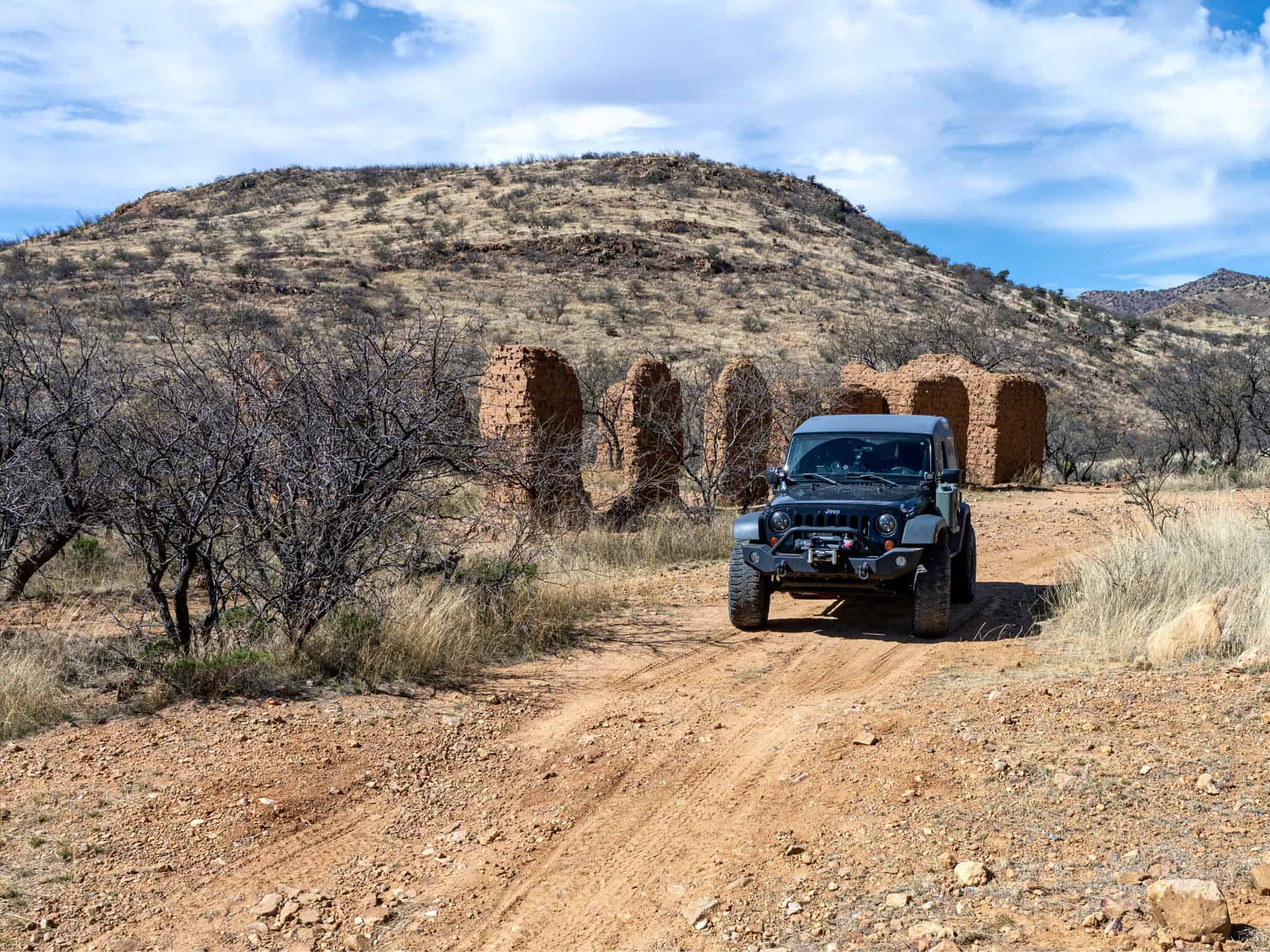 jeep wrangler parked in front of ghost town ruins in southern arizona