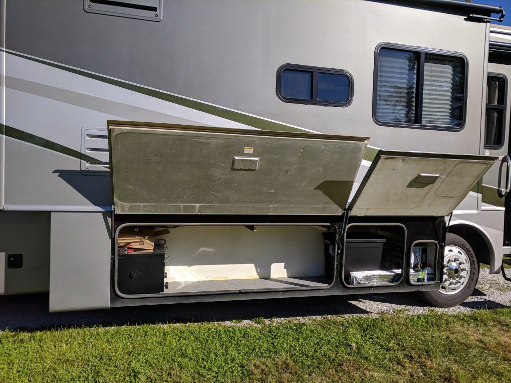 buying thoughtful gifts for rvers is important because anything that doesn't fit inside has to be stored outside. photo of a motorhome basement with open bay doors.